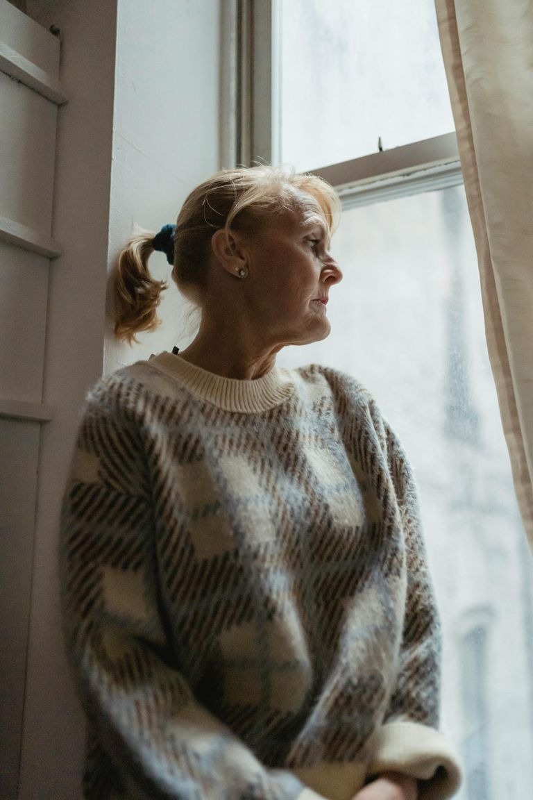 An upset senior woman looking out the window | Source: Pexels