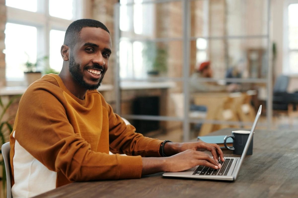 A smiling man with a laptop | Source: Pexels